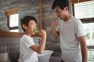 a father and son brushing their teeth together