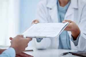 Medical professional handing clipboard to patient