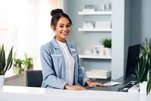 Happy dental team member standing behind front desk