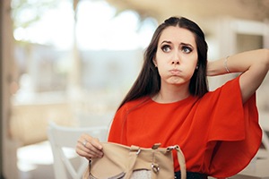 Confused young woman searching her purse