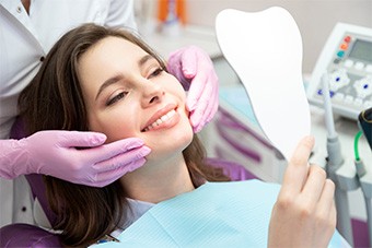 patient smiling while holding dental mirror