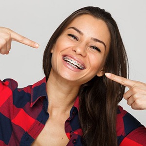 Happy young woman pointing at her orthodontic braces