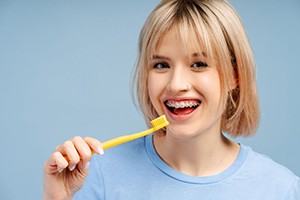 Woman with braces holding a yellow toothbrush